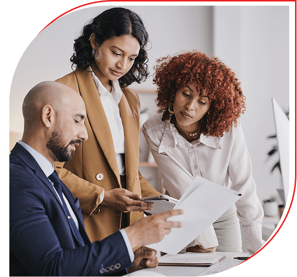 Three professionals reviewing documents in a collaborative work setting.