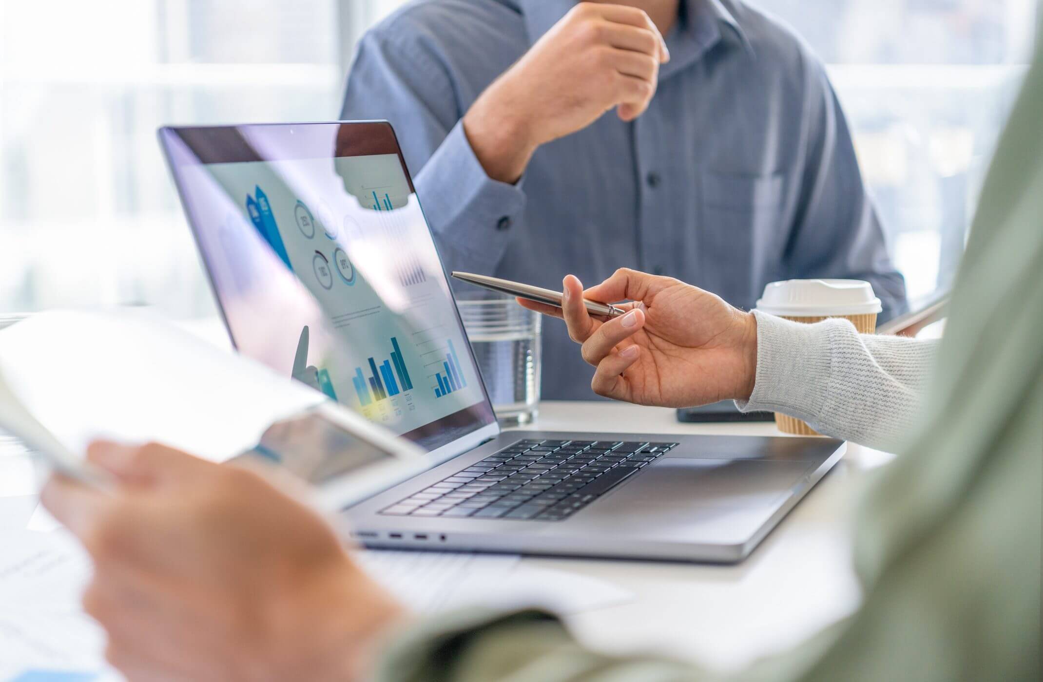 Two people discussing data charts on a laptop during a meeting.