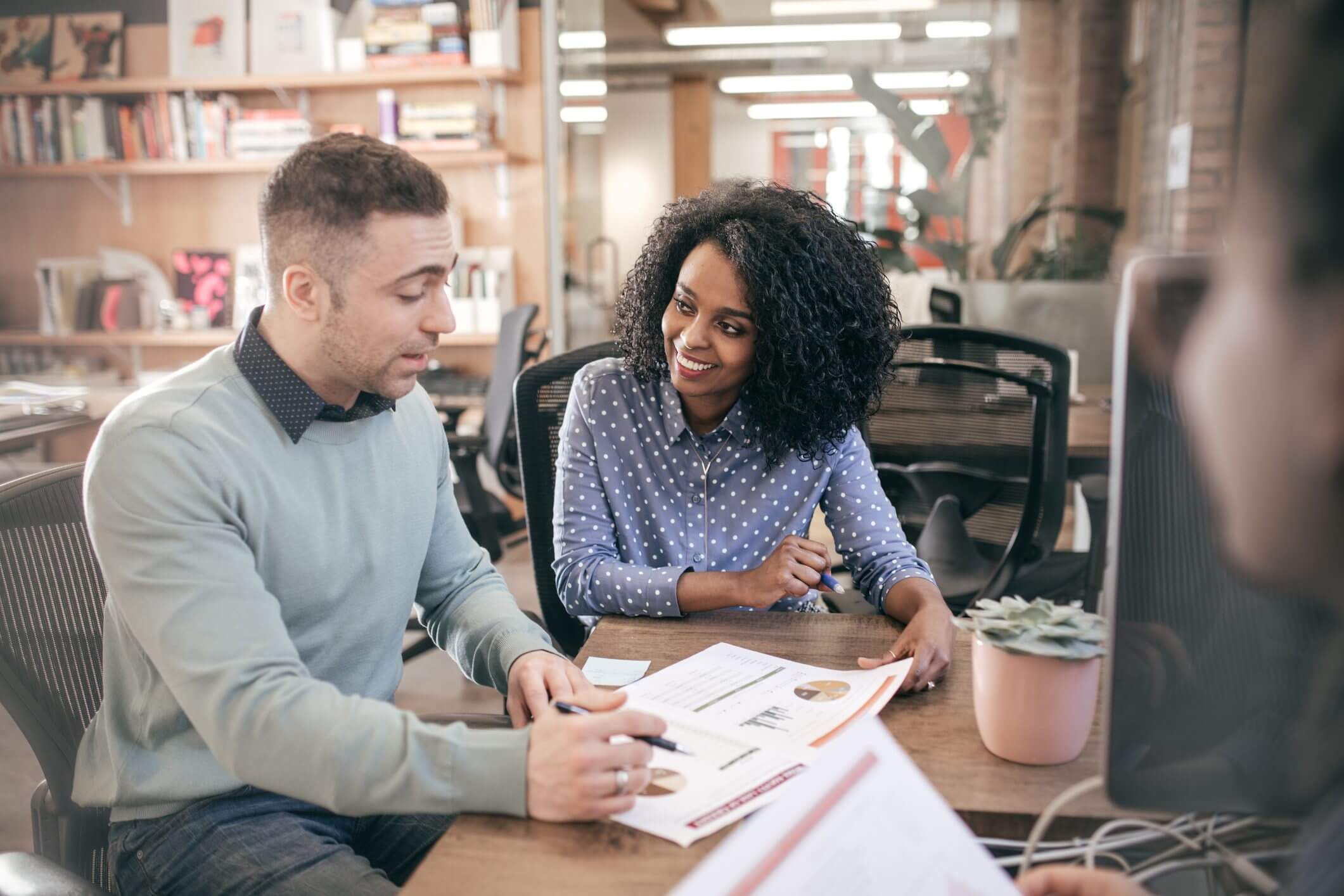 Colleagues discussing documents in a modern office setting.