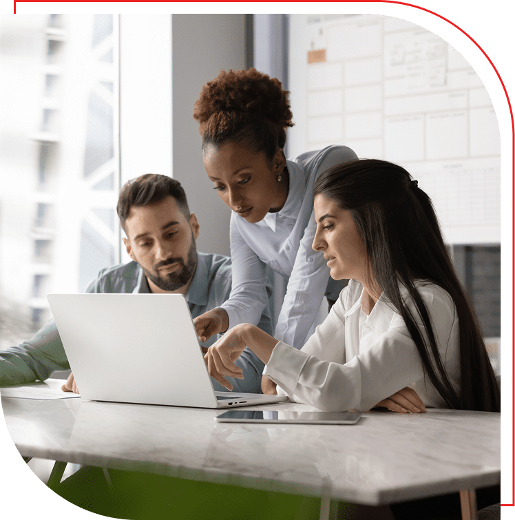 Three coworkers collaborating on a laptop in a modern office.